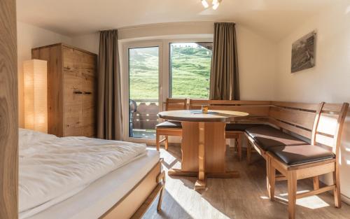 a bedroom with a bed and a table and a window at Haus Himmelreich in Hirschegg