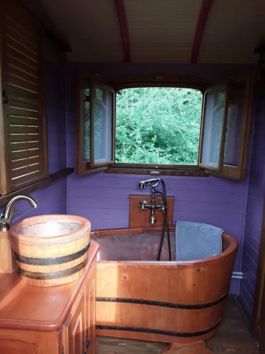 a bathroom with a wooden tub and a window at la roulotte de l'ami nature in Barrais-Bussolles