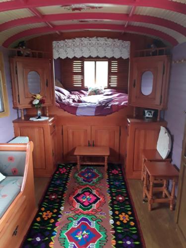 Cette petite chambre comprend un lit et un tapis. dans l'établissement la roulotte de l'ami nature, à Barrais-Bussolles