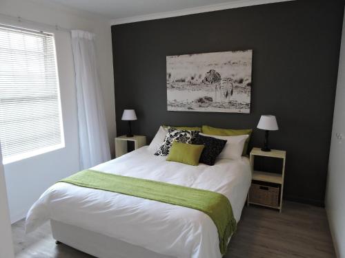 a bedroom with a large bed with a green blanket at Capevistas High Cape in Cape Town