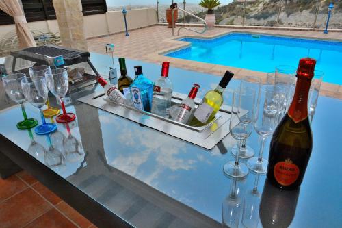 un bar con bicchieri da vino e bottiglie e una piscina di Villa Ocean Breeze a Peyia