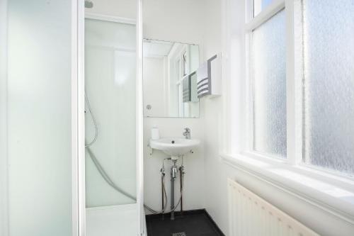 a white bathroom with a sink and a window at Apótek Guesthouse in Akureyri