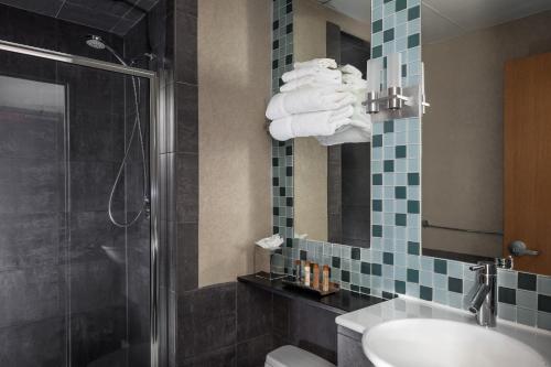 a bathroom with a sink and a shower and towels at Charlesmark Hotel in Boston