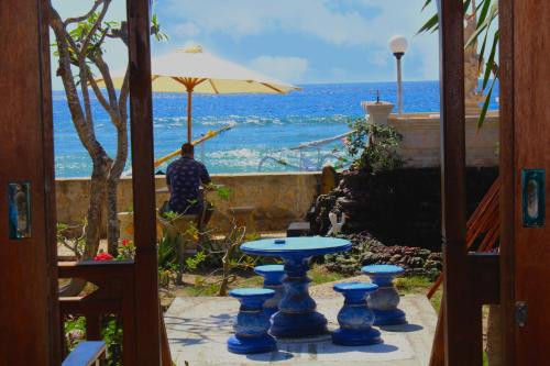 a man sitting at a table with an umbrella at Swan Beach Inn in Nusa Penida