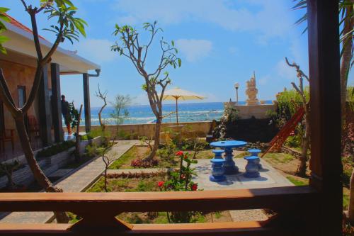 a view of a garden with a table and the ocean at Swan Beach Inn in Nusa Penida
