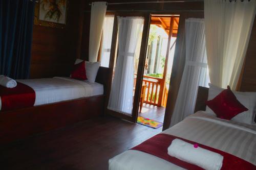 a bedroom with two beds and a door to a balcony at Swan Beach Inn in Nusa Penida
