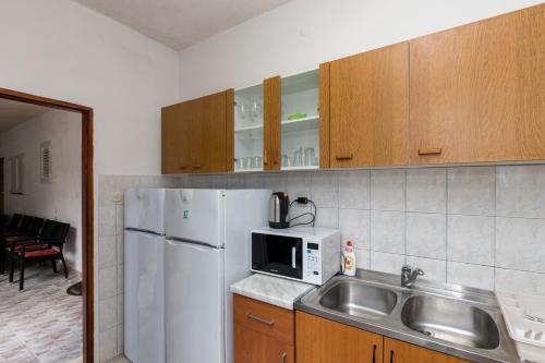 a kitchen with a sink and a white refrigerator at Villa Marija - Sea View Rooms in Molunat