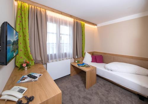 a hotel room with a bed and a television at Hotel zum Hirschen Zell am See in Zell am See