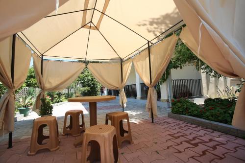 a patio with a table and stools under a tent at Talo's Guest House in Makhinjauri