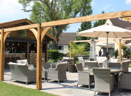 a patio with a table and chairs and an umbrella at The Bear Of Rodborough Hotel in Stroud