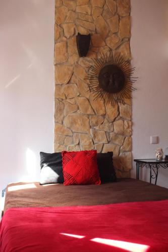 a bedroom with a stone wall and a bed with a red pillow at Casa Marreiros Holiday Home in Vila do Bispo