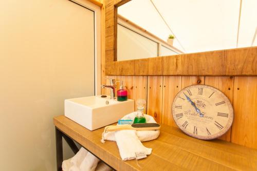 a bathroom with a sink and a clock on a counter at Georgioupolis Beach Hotel in Georgioupolis