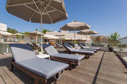 a row of lounge chairs and umbrellas on a deck at Georgioupolis Beach Hotel in Georgioupolis
