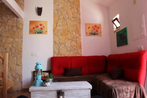 a living room with a red couch and a stone wall at Casa Marreiros Holiday Home in Vila do Bispo