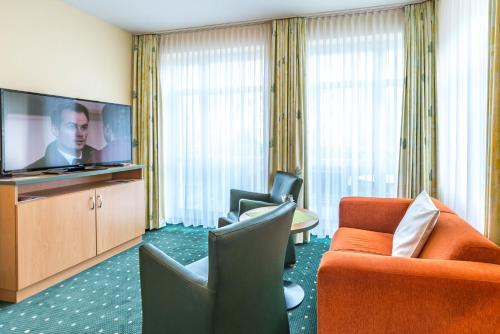 a hotel room with a couch and chairs and a flat screen tv at Am Weststrand Aparthotel Kühlungsborn in Kühlungsborn