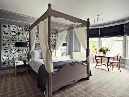 a bedroom with a canopy bed and a table at Rum Doodle, Windermere B&B in Windermere