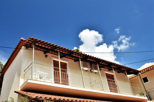 a white house with a balcony and a blue sky at Petros Giatras - Rooms in Zakynthos Town