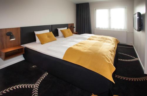 a bedroom with a large bed with a yellow blanket on it at Best Western Plus Hotel Eyde in Herning