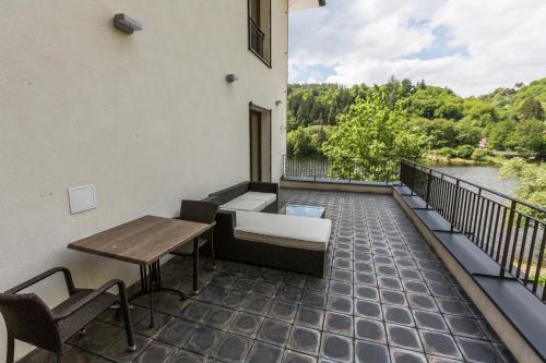 a balcony with a table and chairs and a view of a river at Hotel Mandát in Hradištko