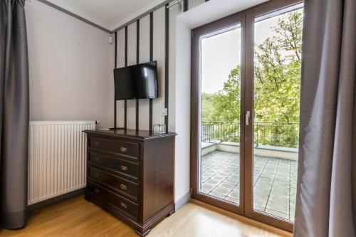 a room with a dresser with a television and a balcony at Hotel Mandát in Hradištko