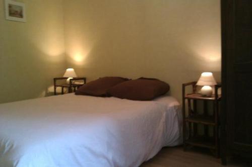 a bedroom with a white bed with two night stands at La petite maison pour 5 personnes in Évran
