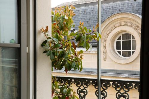 a window with a reflection of a building and a mirror at Hôtel Les Dames du Panthéon in Paris