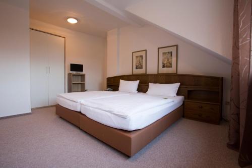 um quarto com uma cama grande e lençóis brancos em Hotel Rhein-Ahr em Remagen