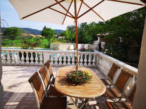 a wooden table and chairs with an umbrella on a balcony at gîte de la Rose in Draguignan
