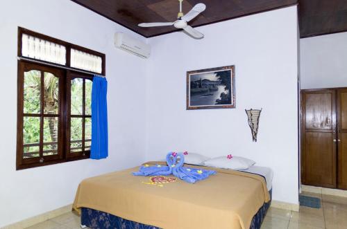 a bedroom with a bed with a blue ribbon on it at Matahari Tulamben Guesthouse in Tulamben