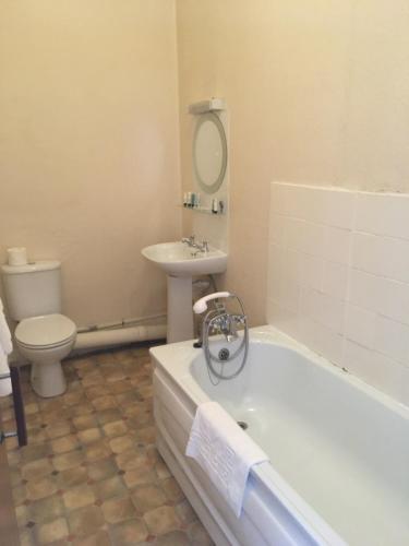 a bathroom with a tub and a toilet and a sink at Hotel Balmoral in Bournemouth