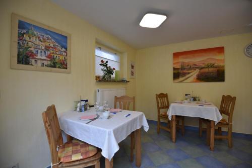 a dining room with two tables with white table cloth at Hotel Haus Orchideental Jena in Jena