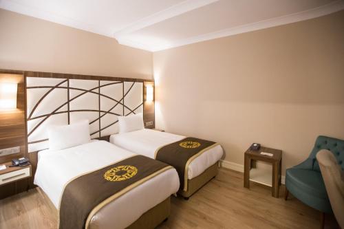 a hotel room with two beds and a chair at The Grand Mira Business Hotel in Istanbul