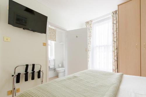 a bedroom with a bed with a flat screen tv on the wall at Hotel Balmoral in Bournemouth