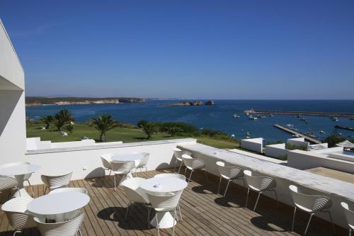 a balcony with white tables and chairs and the ocean at Memmo Baleeira - Design Hotels in Sagres