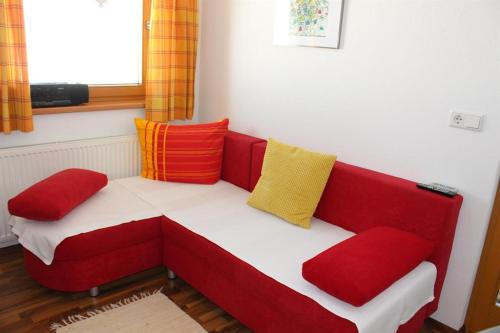 シュトゥンムにあるFerienwohnung Hollaus Elisabethの赤いソファ(カラフルな枕付)