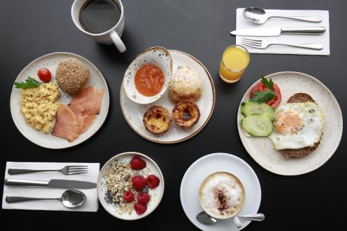 a table topped with plates of breakfast foods and utensils at Memmo Baleeira - Design Hotels in Sagres