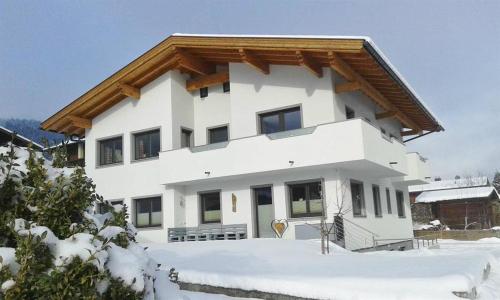 a white house with a wooden roof in the snow at Schweinberger Sixtus in Aschau