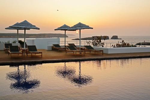 a group of chairs and umbrellas next to a body of water at Memmo Baleeira - Design Hotels in Sagres