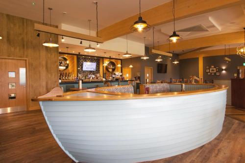 a bar with a large white counter in a restaurant at Drimsynie Estate Hotel in Lochgoilhead