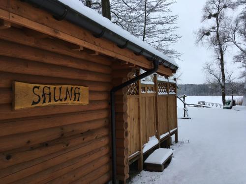 a sign on the side of a log cabin in the snow at Stajnia Sarnówek Nad Jeziorem Różany in Rozajny Wielkie