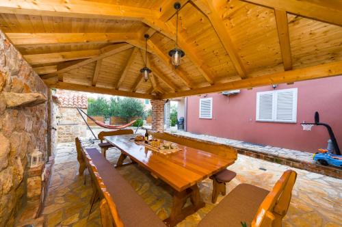 un comedor al aire libre con mesa de madera y bancos en Apartments Orkula, en Maslenica