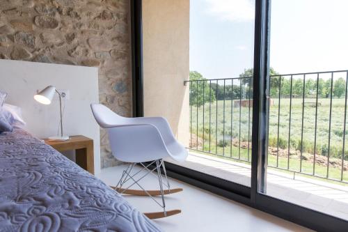 a bedroom with a white chair and a large window at Can Parés in Sant Gregori