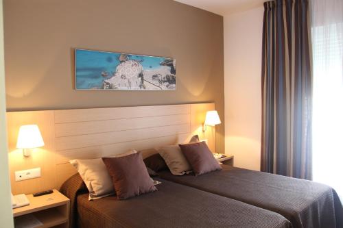 a hotel room with a bed and two lamps at Mena Plaza in Nerja