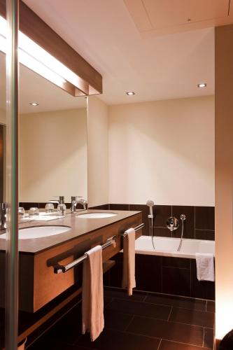 a large bathroom with two sinks and a tub at Posthotel Walhalla Regensburg Ost in Donaustauf