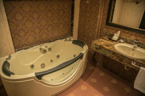 a bathroom with a large tub and a sink at Queens Suite Hotel in Beirut