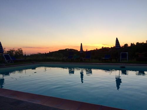 a swimming pool with the sunset in the background at Agriturismo La Palazzina in Palaia