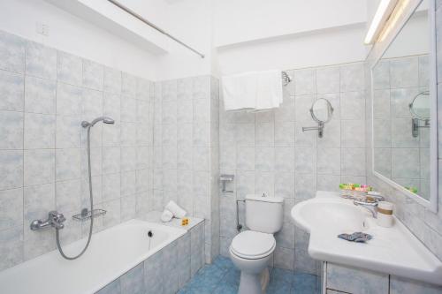 a bathroom with a toilet and a tub and a sink at Mon Repos Hotel in Faliraki