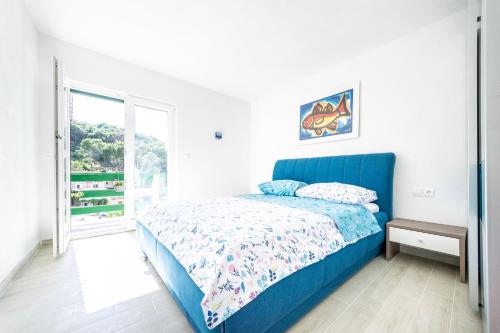 sypialnia z niebieskim łóżkiem i oknem w obiekcie Apartmani Ada 1 w mieście Povlja