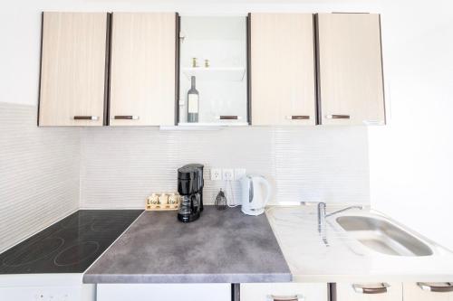 a kitchen with white cabinets and a coffee maker on a counter at Apartmani Ada 1 in Povlja
