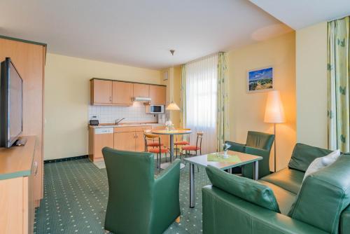 a living room with a couch and a table and a kitchen at Am Weststrand Aparthotel Kühlungsborn in Kühlungsborn